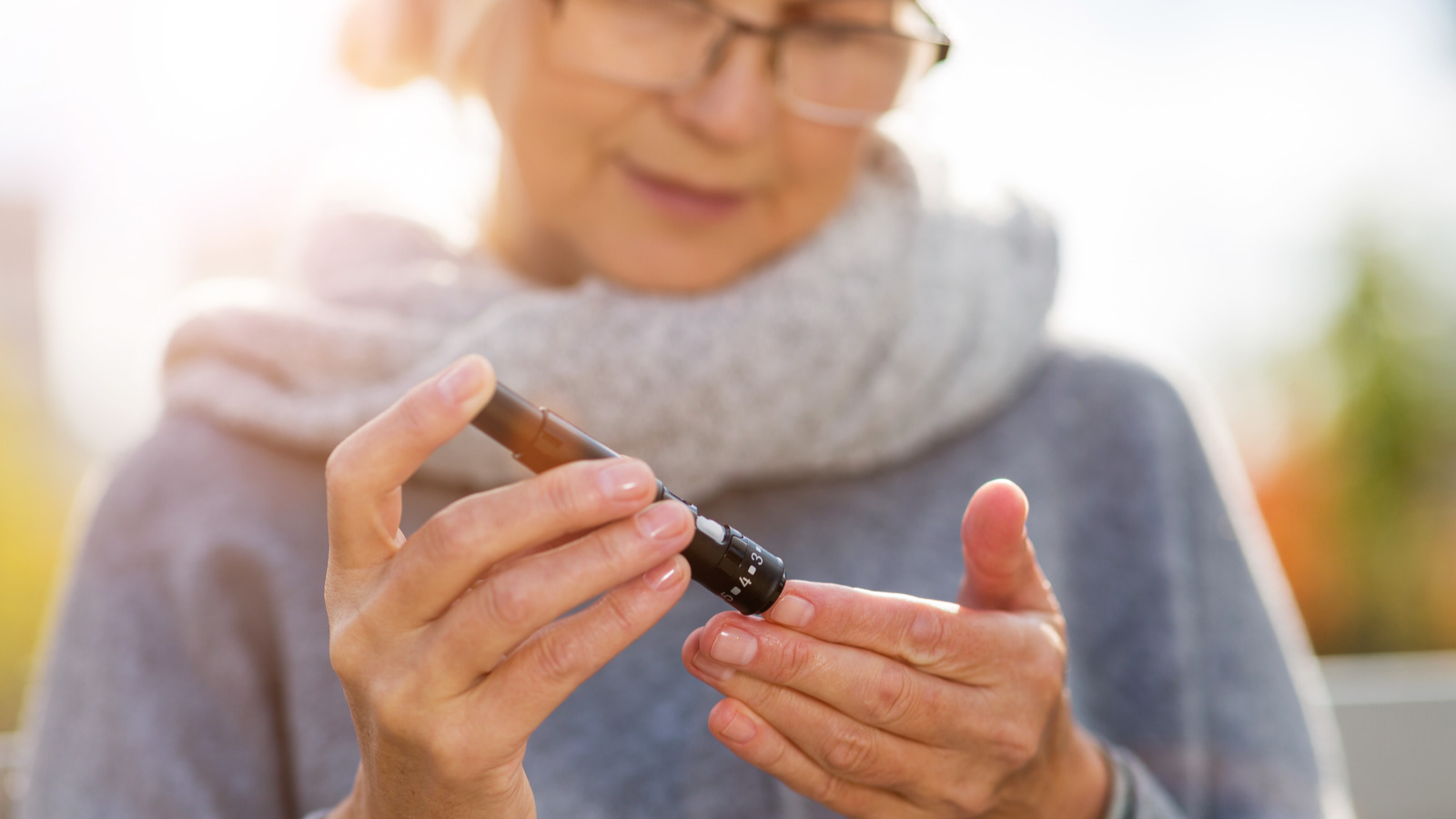 Older white woman using a device to prick her finger and test her blood sugar
