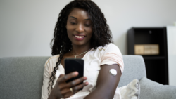 Woman looking at her phone while wearing a glucose monitoring device
